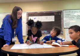 A University of South Florida education student works with three Pepin Academies students during a small-group classroom activity, providing individualized instruction and collaborative learning support.